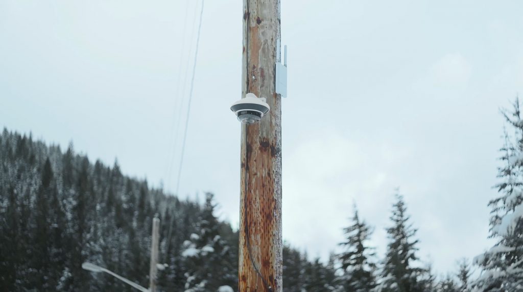 CCTV camera mounted on a pole in snowy, wooded Denver landscape, illustrating environmental challenges for security installations.