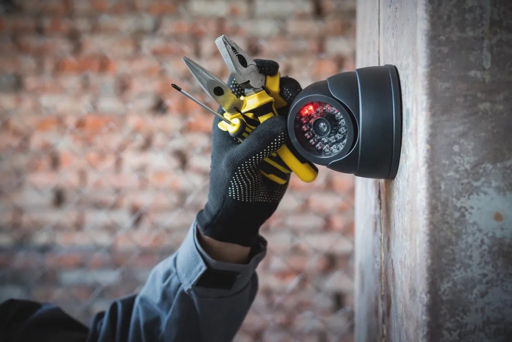 Technician installing a CCTV camera with tools in hand, showcasing a successful security installation by Secure Communications Group in Denver.