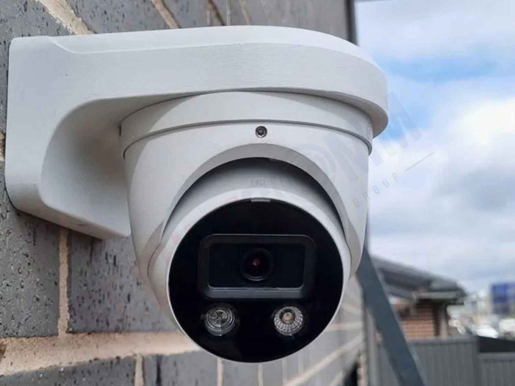 White PTZ camera mounted on a brick wall, illustrating the cost considerations for these security systems.