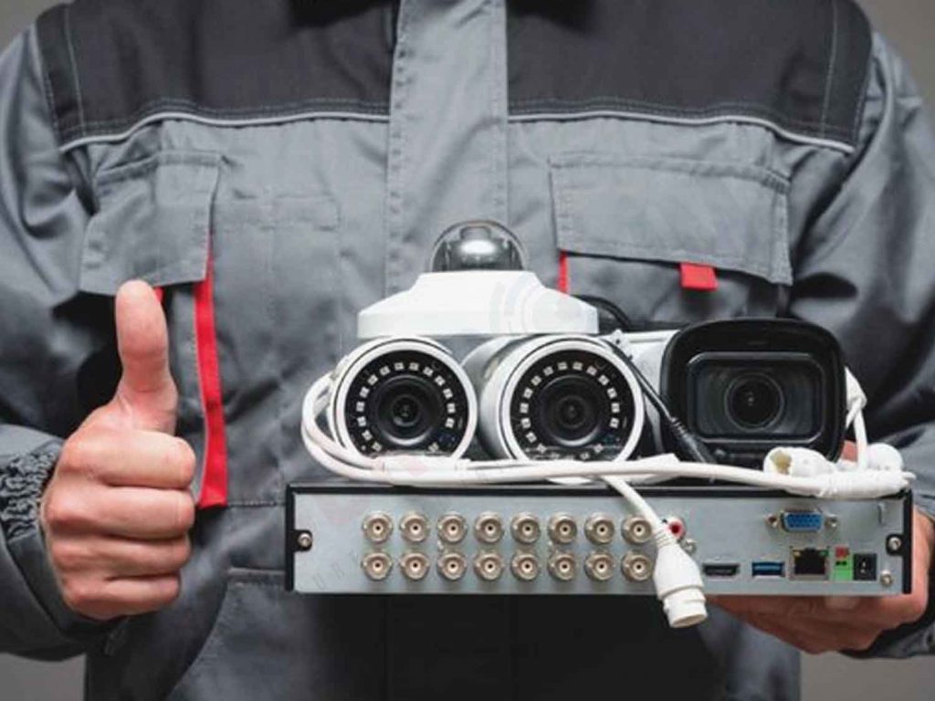 Technician holding CCTV equipment, including PTZ cameras and a DVR, representing the decision-making process for choosing the right system.